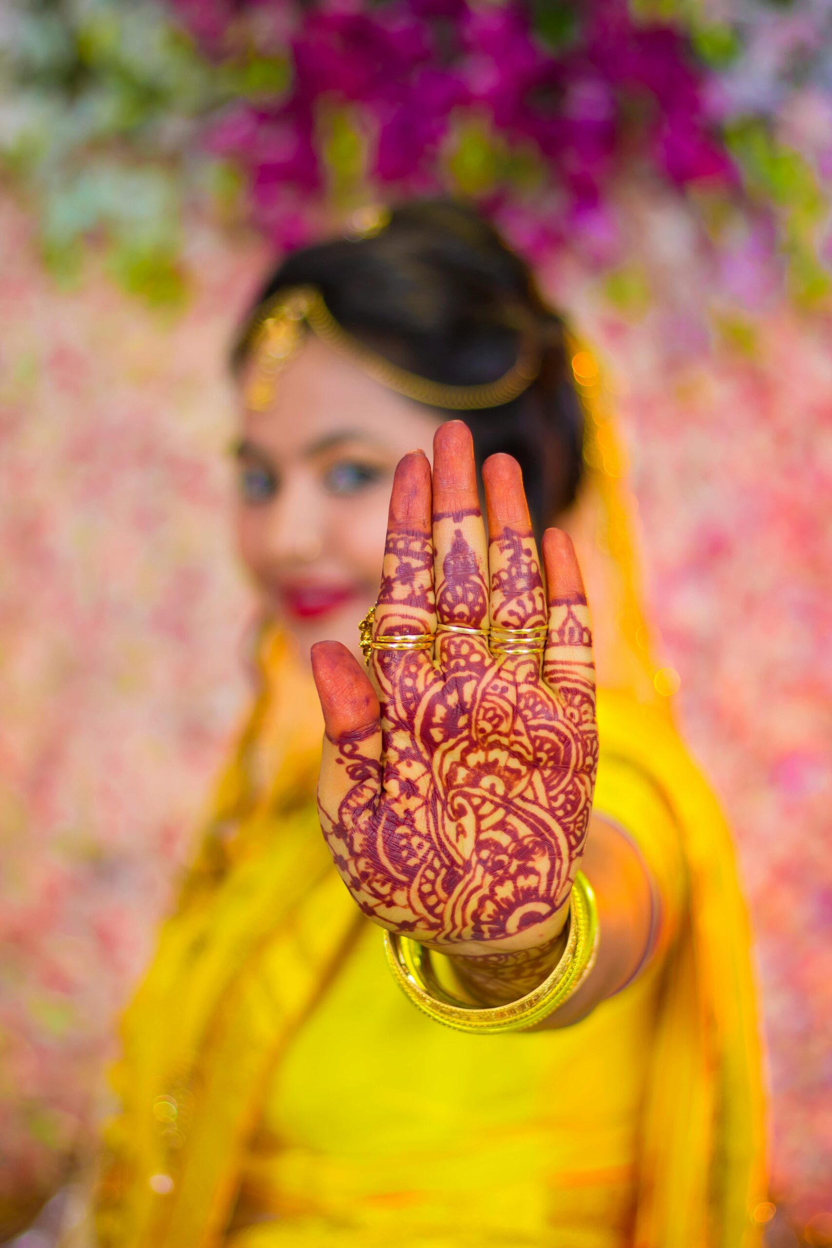Vibrant portrait of an Indian woman showcasing intricate mehndi design on her hand, colorful background.